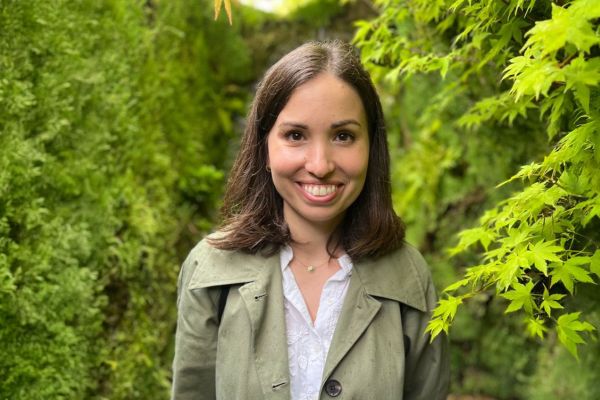 Portrait of Tiziana standing in a lush green garden surrounded by vibrant foliage.