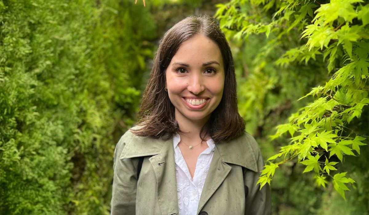 Portrait of Tiziana standing in a lush green garden surrounded by vibrant foliage.